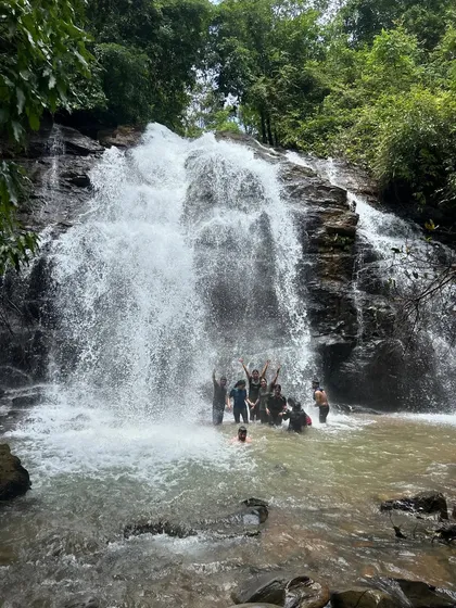 The whole group celebrating under the cascading water. Moments like these are what make our monsoon treks so special.