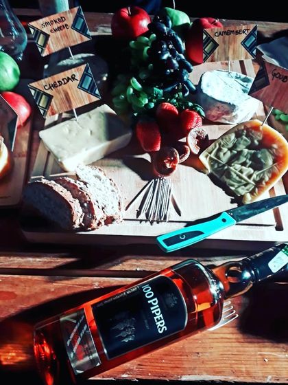 We can also curate tasting experiences for you and your guests. This setup shows a classic pairing of 100 Pipers Scotch Whisky with a carefully selected cheese board, including cheddar, gouda, and camembert.