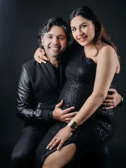 A glamorous studio portrait of an expecting couple. The mom-to-be shines in a black sequin dress while her partner holds her close, creating a timeless and elegant memory.