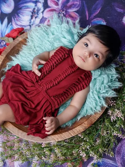 A beautiful composition showing the baby nestled in a bowl surrounded by delicate flowers, creating a lovely, artistic portrait.