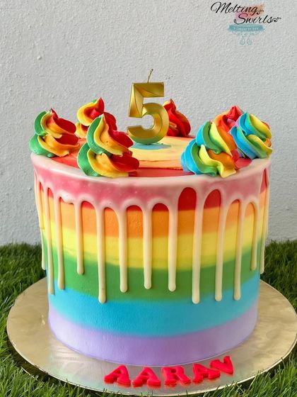 We love making rainbow cakes with whipped cream. This one features bright rainbow stripes, a white chocolate drip, and rainbow-colored swirls on top.
