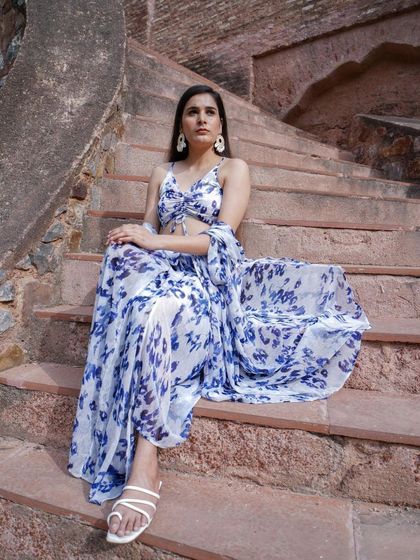 A model wearing a beautiful blue and white floral co-ord set with a matching cape from The Kiki Tribe.