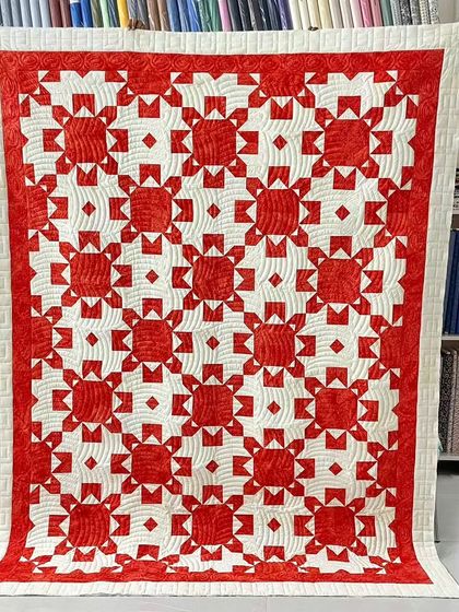 A gorgeous red and white star quilt with intricate custom quilting in the open spaces.