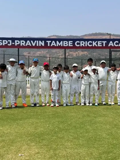A wide shot of our players assembled on the lush green field, with the official academy banner in the background. This is where future stars are made.