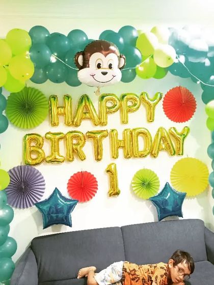 A cute and simple jungle theme setup for a first birthday at home. The balloon arch is decorated with a monkey foil balloon and fairy lights for a touch of sparkle.