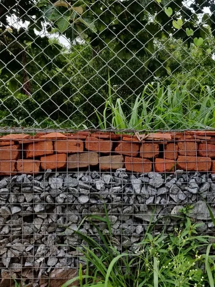 A close-up of the Gabion wall at Cheerville. We filled the wire mesh cage with waste stones from a local quarry and broken bricks from the site. This method is cost-effective, reduces carbon emissions, and allows for water percolation.