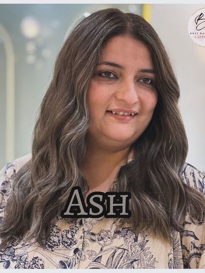 A happy client showcasing her new, elegant, and modern ash hair color.