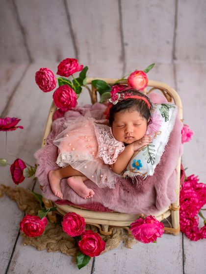 This little one is sleeping on a tiny rattan bed, surrounded by beautiful pink flowers. It looks like a scene from a fairytale.
