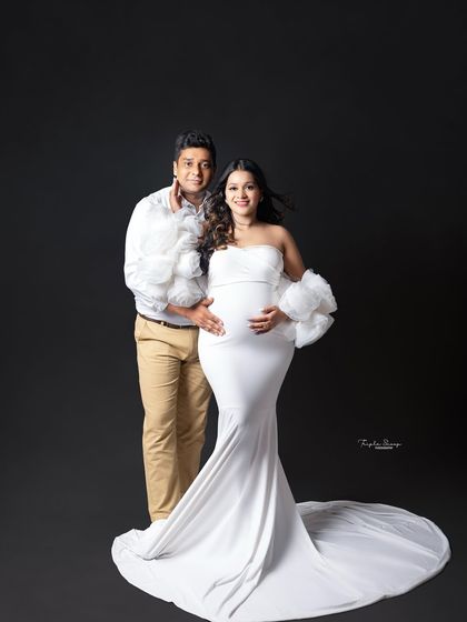A full-length portrait showcasing a stunning white maternity gown against a classic black background. This creates a timeless and elegant look.
