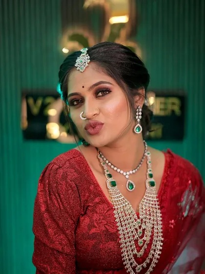 A playful and confident shot of the bride in her red reception outfit. The puff-sleeve blouse adds a touch of modern trendiness, while the magnificent layered diamond necklace ensures the look remains timelessly elegant.