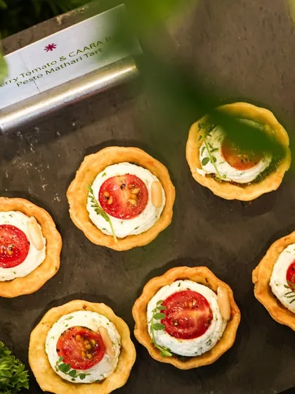 Our popular cherry tomato and CAARA basil pesto mathri tarts. This canapé is a modern Indian twist on a classic, combining familiar flavors in a new and elegant format for catered events.