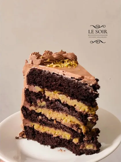 A close-up of my Pistachio Kunafa Chocolate Cake slice, inspired by the viral Dubai chocolate. It features layers of rich chocolate cake, creamy pistachio filling, and the signature crunchy kunafa texture.