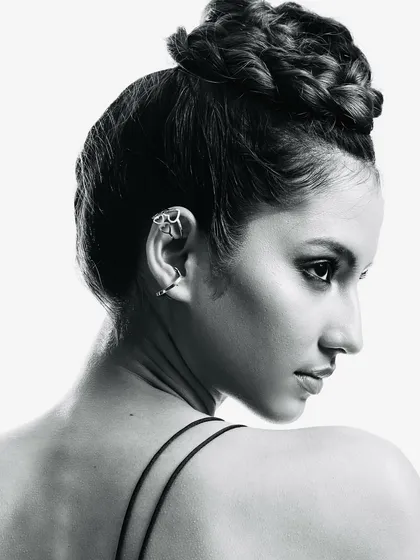 A closer look at the braided bun and the striking profile. The absence of color draws attention to the texture of the hair and the unique ear cuff.