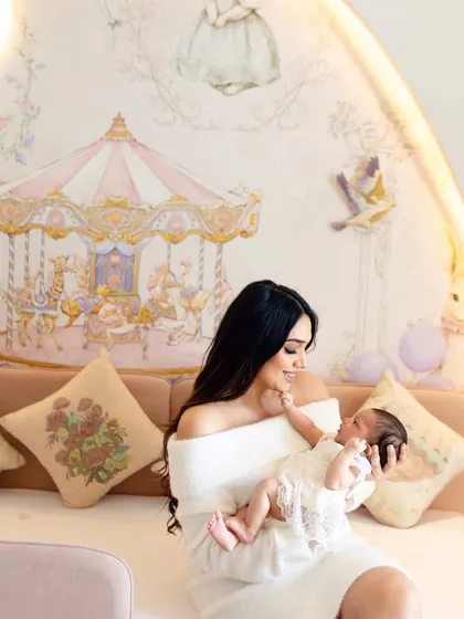 A mother and her newborn in a beautifully designed nursery. We can hold the session right in your home, capturing your new life in the space you created for your baby.
