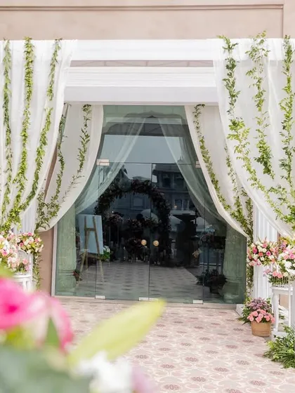 A grand entrance to the Haldi ceremony, with sheer white curtains and fresh green garlands creating an elegant and refreshing look.