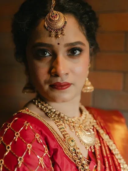 A stunning close-up portrait. The makeup is bold yet elegant, perfectly complementing the intricate temple jewellery and her natural features.
