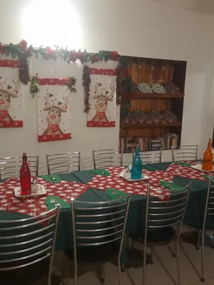 A long table set for a large group gathering during the Christmas season, complete with reindeer wall hangings.