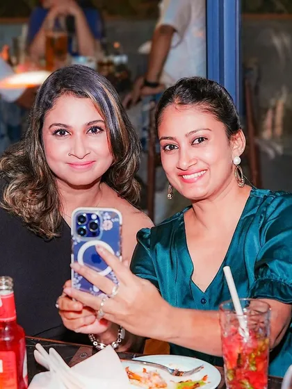 Two friends taking a selfie at their table.