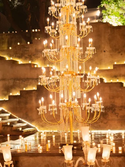 A magnificent tiered crystal chandelier stands as a centerpiece, surrounded by the warm glow of hundreds of candles lining the steps of the heritage venue.