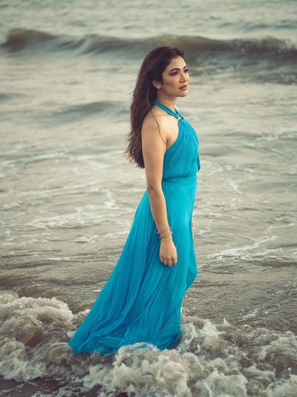 A serene profile shot of the model standing in the water, creating a timeless and elegant beach portrait.