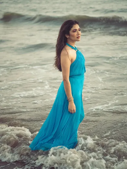A calm, elegant portrait of Ridhima Pandit. The flowing blue dress contrasts beautifully with the churning water of the sea.