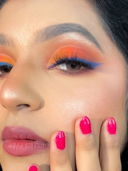 A close-up of the creative eye makeup, showing the sharp blue winged liner against the bright orange eyeshadow.