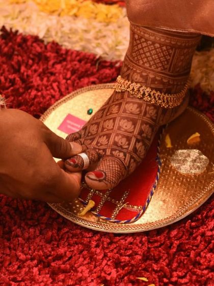 A close-up of the toe-ring ceremony, giving a beautiful view of the intricate lotus grid mehendi on the bride's foot.