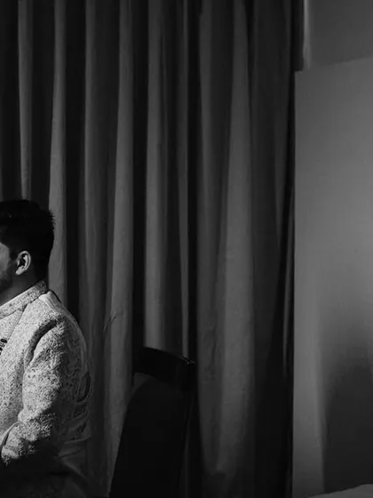 A quiet, contemplative portrait of the groom in black and white. The simple composition and the use of shadow give this image a timeless, cinematic quality.