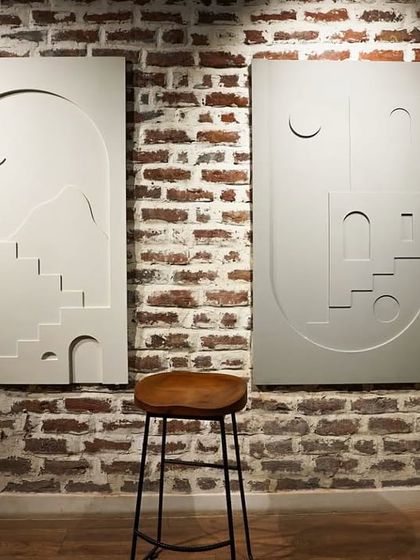 The 'Ashta Prahar' wall murals displayed against a rustic brick wall. The contrast highlights the clean, modern lines of the sculpted panels.