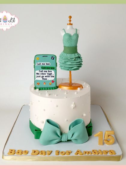 A stylish cake for Amaira's "Bae Day," celebrating her 15th birthday. It features a mannequin with a tiered dress and a fondant smartphone displaying a trendy message.