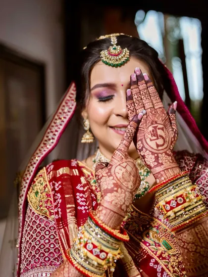 A playful and happy moment captured. The bride's intricate mehendi and soft glam makeup with shimmery pink lids create a beautiful, joyful bridal portrait.
