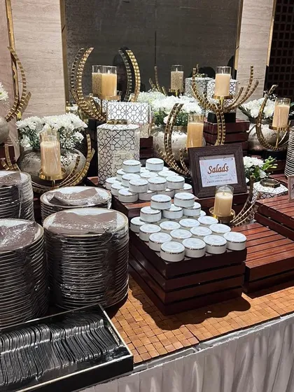 A detailed shot of a buffet station. The use of metallic and geometric decor elements, along with candlelight, adds a layer of sophistication and warmth to the setup.