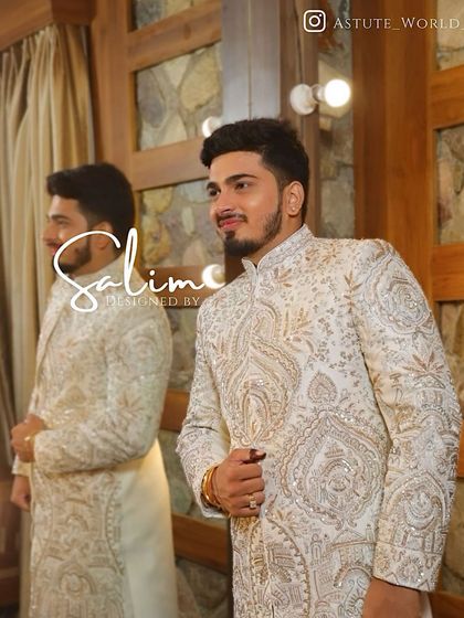 A client looking sharp in a custom-fitted ivory sherwani. The fabric has a subtle woven pattern and is covered in intricate silver and gold paisley embroidery.