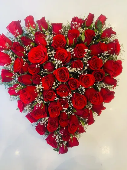 A stunning heart-shaped arrangement made entirely of vibrant red roses and a sprinkle of baby's breath. This is a classic and powerful romantic gesture.