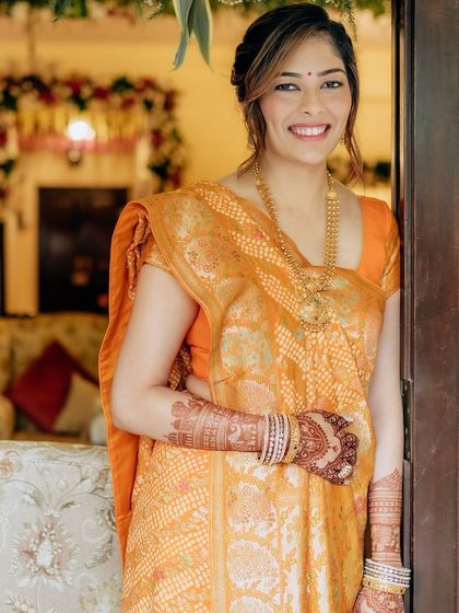 For her Mandvo ceremony, we opted for an elegant and traditional look. The makeup is clean and radiant, complementing her beautiful orange saree.