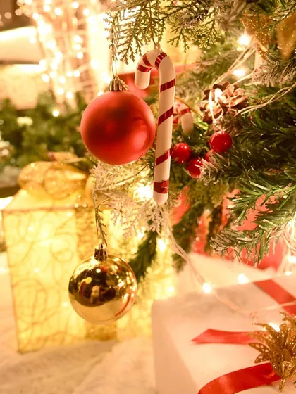 A close-up of the classic Christmas tree ornaments, including red and gold baubles and a candy cane, creating a feeling of nostalgia and holiday cheer.