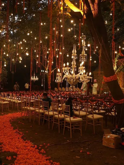 Ambiance is everything, especially after the sun goes down. I transformed this outdoor space into an enchanted forest with strings of marigolds, hanging bulbs, and elegant chandeliers, creating a warm and magical setting for an evening ceremony.