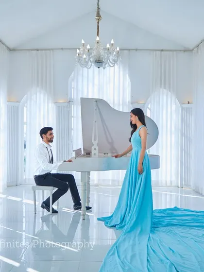 Our all-white studio, complete with a grand piano, provides a backdrop for timeless elegance. The flowing trail of this light blue gown adds a touch of drama and sophistication to this classic couple portrait.