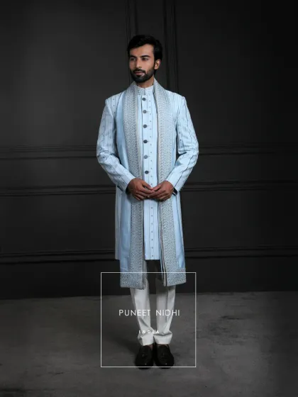 This ice blue achkan is a tale where pin-tucked lines echo discipline and threadwork whispers devotion. It is crafted for the man who wears not just fashion, but legacy.