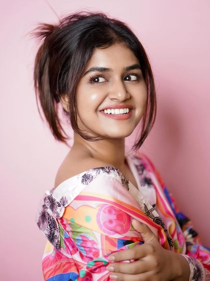 A fun and vibrant studio portrait. The colorful top and pink background create a playful and energetic mood, perfect for a youthful portfolio.