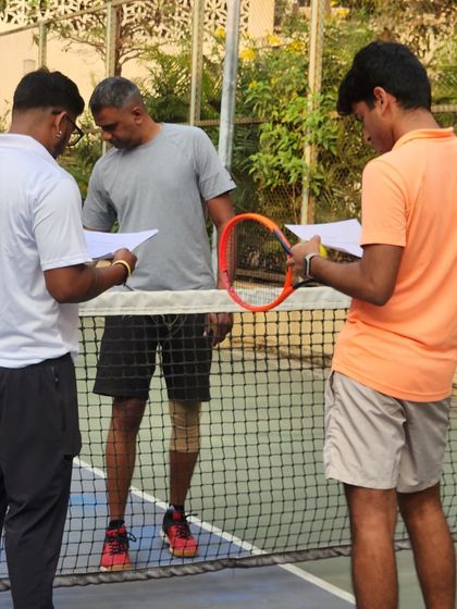 Our coaches discuss strategy on the tennis court. We are excited about our new tennis programs, where we help players of all levels serve strong and smash their goals.