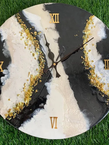 A striking black, white, and beige resin clock with bold gold accents. This piece makes a strong decorative statement.