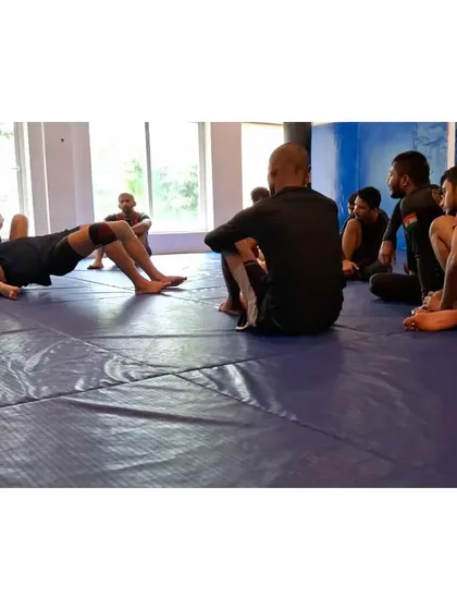 A coach demonstrating a bridging escape from mount, a fundamental survival technique in both BJJ and MMA.
