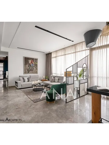 The living room of Apartment 704 is kept minimal with a grey sofa and contrasting green lounge chairs. Full-height glazing allows ample natural light, making the space feel larger.