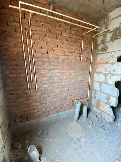 Before: A bathroom space during the early plumbing and construction phase, showing the bare brick walls.