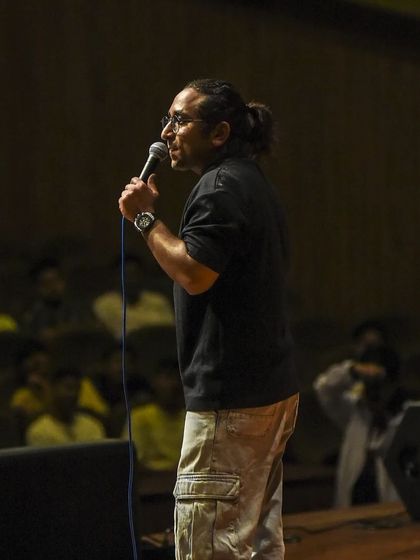 A side view of Appurv Gupta on stage, showing his comfortable and confident presence.