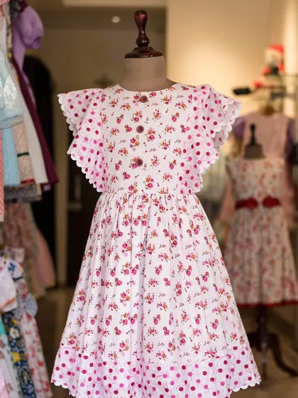 A playful mix of patterns, this dress combines a delicate floral print on the bodice with a fun polka dot skirt. The flutter sleeves add a touch of whimsy.