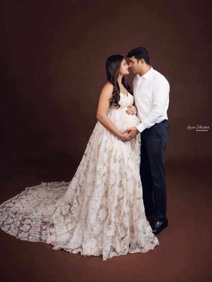 A classic and elegant couple's portrait. The contrast between the intricate white lace gown and the simple, dark suit creates a timeless and sophisticated look.