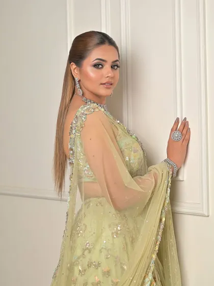 A confident pose in a stunning pastel mint lehenga. The makeup is glamorous yet sophisticated, highlighting her features beautifully.