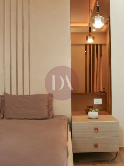 A close-up of a bedroom design focusing on texture and warmth. The fluted wall paneling behind the bed is complemented by a sleek wooden nightstand and a modern pendant light, creating a calm, contemporary feel.